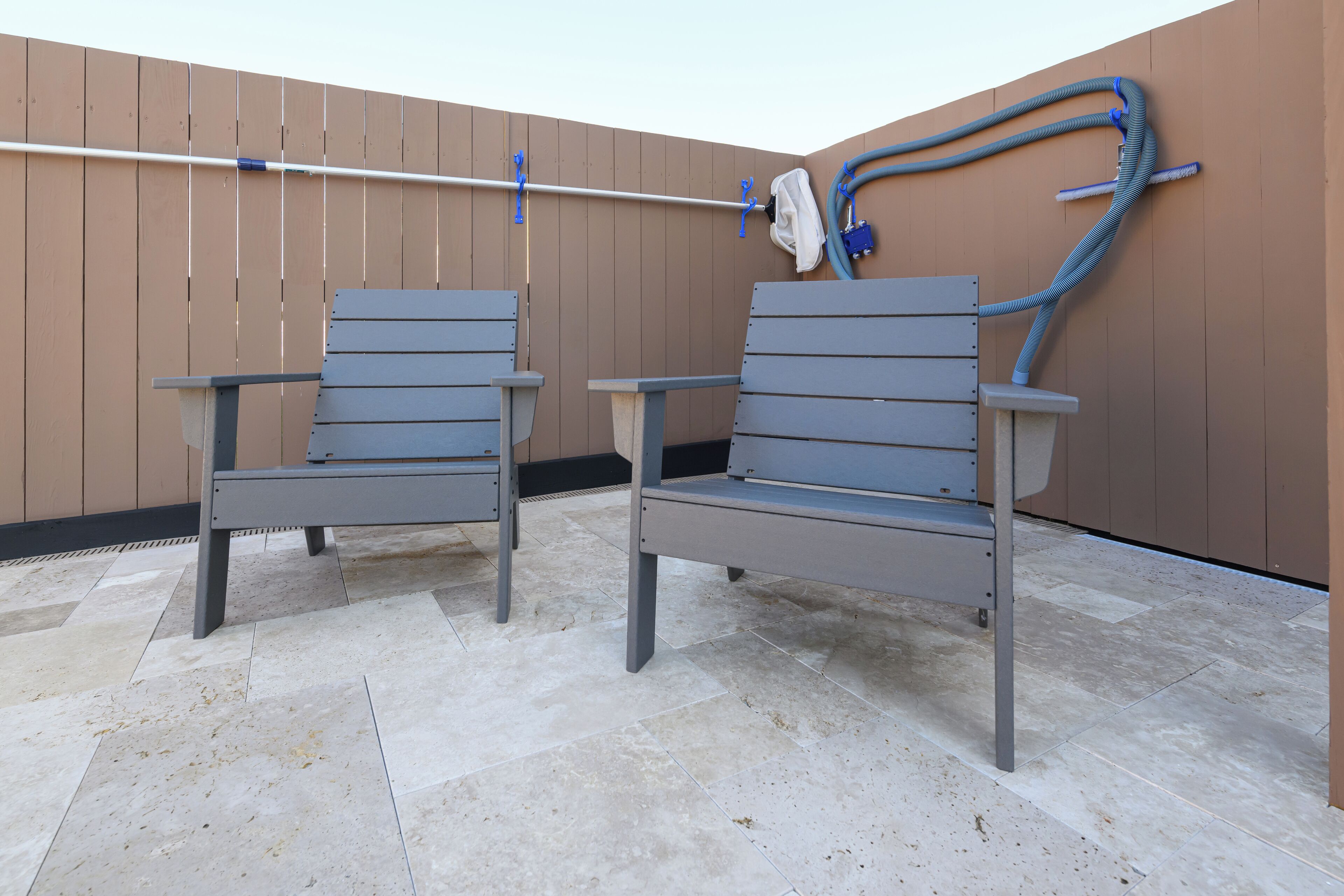 Two grey chairs with metal frames and a towel hanging on a metal rod.