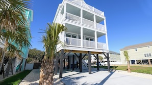 A multi-story building with a balcony on the second floor, a covered area with stairs leading up to it, and a palm tree in the foreground. - BIG VIEW. New 2026. 7 BR/7.5 BT, private 25'x15' pool, elevator, Surfside Beach (Surfside Beach)