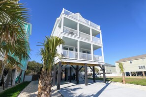 A multi-story building with a balcony on the second floor, a covered area with stairs leading up to it, and a palm tree in the foreground. - BIG VIEW. New 2026. 7 BR/7.5 BT, private 25'x15' pool, elevator, Surfside Beach (Surfside Beach)