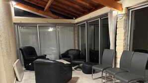 A sunlit patio with black leather chairs and a table, a radiator, and a stone wall. - Leisure center and swimming pool 5 minutes away. Town center and Hyper U center 400m away. (Parthenay)
