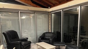 A modern patio area with leather furniture, including a sofa and chairs, a small table, and a round ottoman. - Leisure center and swimming pool 5 minutes away. Town center and Hyper U center 400m away. (Parthenay)