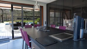 A modern kitchen with a large island, stainless steel appliances, and a view of the outdoors.
