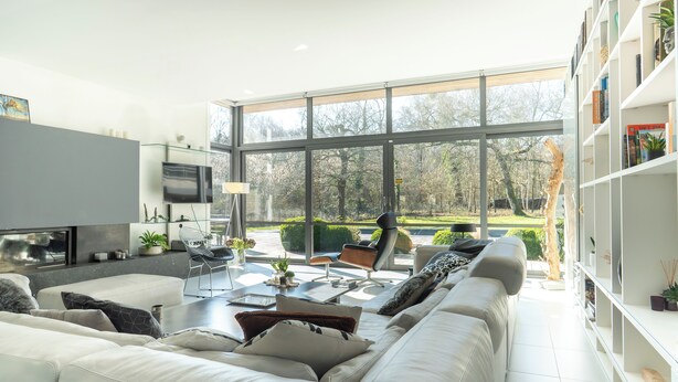 A modern living room with a large window, a flat-screen TV, and a bookshelf.