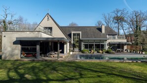 A modern house with a swimming pool, a covered patio, and a large deck area.