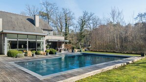 A modern house with a swimming pool, a deck, and a garden.