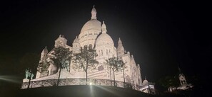 A large, illuminated building with multiple domes and towers, surrounded by trees. - Apartment near Sacré-Cœur (Paris)