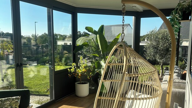 Ein geräumiger Balkon mit Hängesessel, Topfpflanzen und Blick auf die Umgebung.