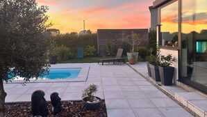 Eine moderne Außenpatio mit Schwimmbecken, Sitzbereichen und Blick auf den Sonnenuntergang.