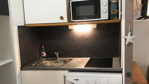 Une cuisine compacte équipée d’un four à micro-ondes, d’un évier et d’un lave-linge.