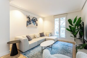 Ein modernes Wohnzimmer mit einer Eckcouch, einem runden Couchtisch und einem großen, abstrakten Gemälde an der Wand.