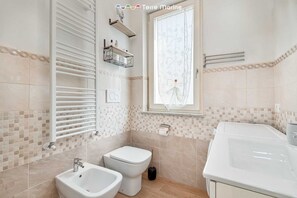 Een douche, een bidet, handdoeken, toiletpapier