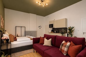 Ein modernes Wohnzimmer mit Sofa, Bett, Küchenzeile und Esstisch.