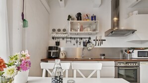 Een moderne keuken met witte kasten, een houten aanrecht en een eethoek met een witte tafel en stoelen.