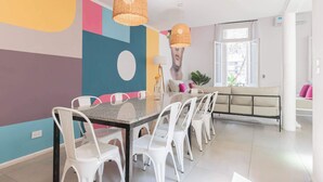 A dining area with a long table, white chairs, and wicker pendant lights. - MOT Rentals + 4Bd with Terrace, Pool & BBQ in La Rural (Buenos Aires)