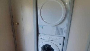 Een kleine wasruimte met een verticaal gestapelde wasmachine en droger.
