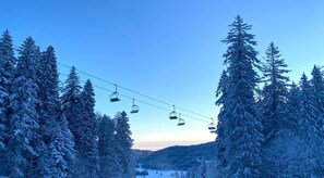 A ski lift with cabins suspended over a snowy forest. - Ô Slopeside chalet in the heart of the Alps (Prémanon)