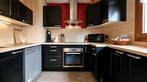 A modern kitchen with black cabinets, a stainless steel dishwasher, an oven, a microwave, and a coffee maker.
