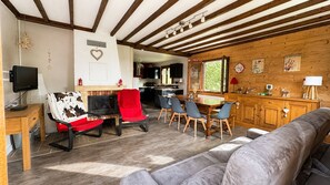 A cozy living room with a fireplace, a television, and a dining area with chairs and a table.