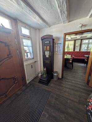 Een kamer met een houten deur, een radiator, een vintage telefoon en een rode bank.