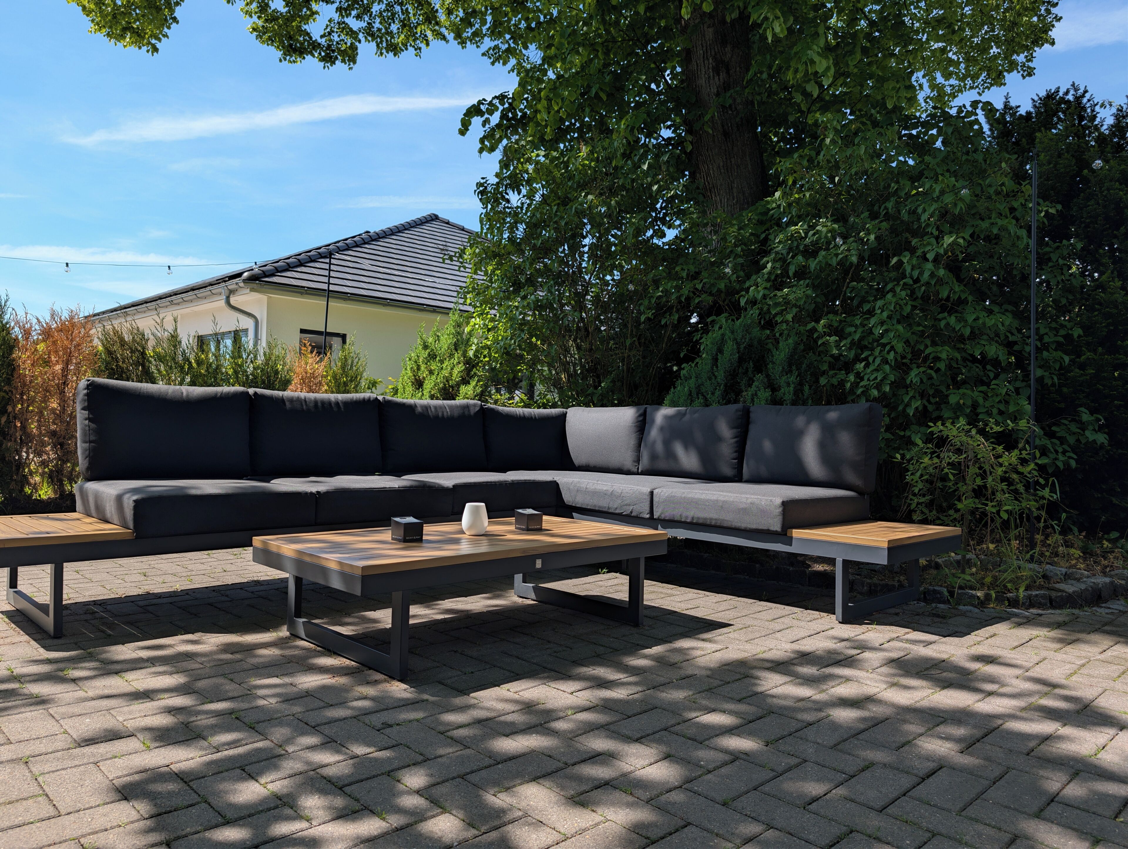 A sectional sofa with a wooden coffee table in an outdoor setting.