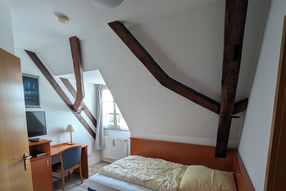 Une chambre à coucher avec un lit, un bureau, une chaise et une fenêtre.