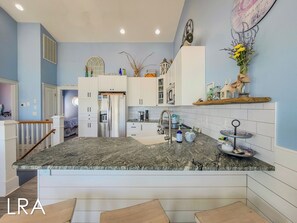 Une cuisine moderne avec des meubles blancs, un plan de travail en granit et un îlot central.
