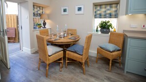 Een eetruimte met een ronde tafel, rieten stoelen en een raam met uitzicht.