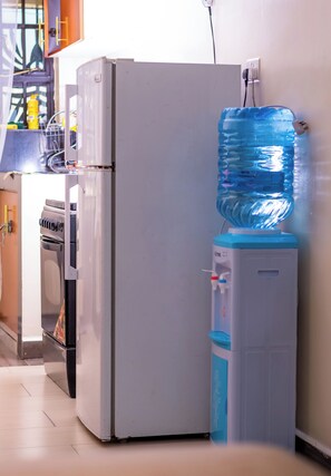 A kitchen with a white refrigerator, a water dispenser, and a microwave. - City Nest 2 Bedrooms City View Apartment (Nairobi)