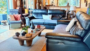 A cozy living room with a leather sofa, wooden coffee table, and a chandelier.