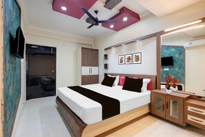 Une chambre à coucher comprenant un lit, un ventilateur de plafond, une armoire, un téléviseur et un miroir.