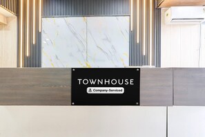 A reception desk with a sign that reads 'TOWNHOUSE Company-Serviced.' - Classic Hotel pix (Jabalpur)