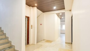 A clean, modern interior with a marble staircase, a wooden ceiling, and a hallway leading to a bright room. - Townhouse Jabalpur View Point (Jabalpur)
