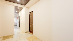A hallway with a wooden door, white walls, and a tiled floor. - Townhouse Jabalpur View Point (Jabalpur)