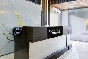 A reception desk with a marble wall and a sign that reads 'TOWNHOUSE Company-Serviced.' - Classic Hotel pix (Jabalpur)