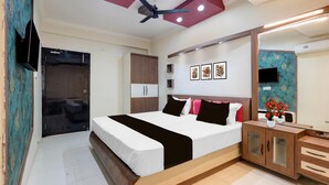 A bedroom with a bed, a ceiling fan, a wardrobe, a TV, and a mirror. - Townhouse Jabalpur View Point (Jabalpur)