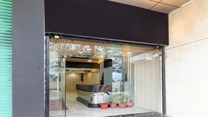 A modern building entrance with a reception desk, potted plants, and a glass door. - Townhouse Jabalpur View Point (Jabalpur)