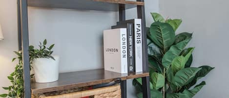 A bookshelf with books and decorative items, including a clock and dried plants.