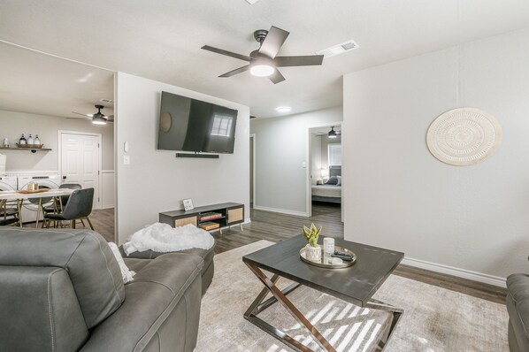 A modern living room with a gray sofa, a coffee table, and a TV mounted on the wall.