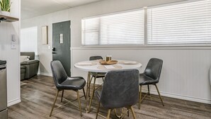 Un comedor con una mesa redonda, cuatro sillas y una ventana con persianas.