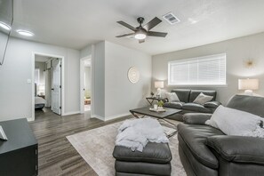 A modern living room with a leather sofa, a coffee table, and a ceiling fan.