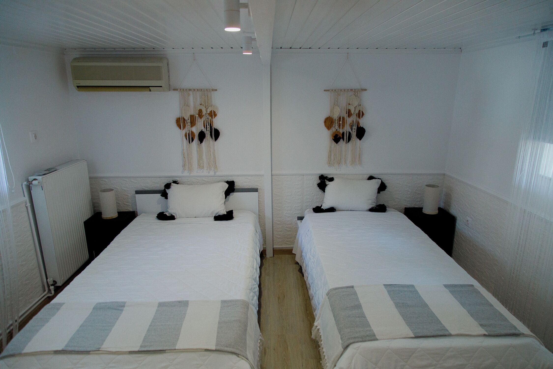 Une chambre d’hôtel avec deux lits, du linge de lit blanc, un radiateur et un climatiseur fixé au mur.