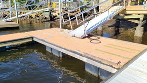 A wooden dock with a metal staircase leading to a wooden platform, surrounded by water and palm trees. - Adorable 2-bedroom house with AC in peaceful Steinhatchee (Steinhatchee)