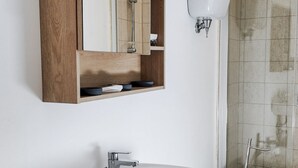 Un baño con un armario de madera, un lavabo blanco y una zona de ducha.