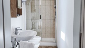 Un baño moderno con un lavabo blanco, un inodoro y una ducha con mampara de vidrio.