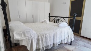 Un dormitorio con cama, armario blanco y una puerta.
