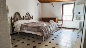 Un dormitorio con cama, una silla, una mesita y un radiador.