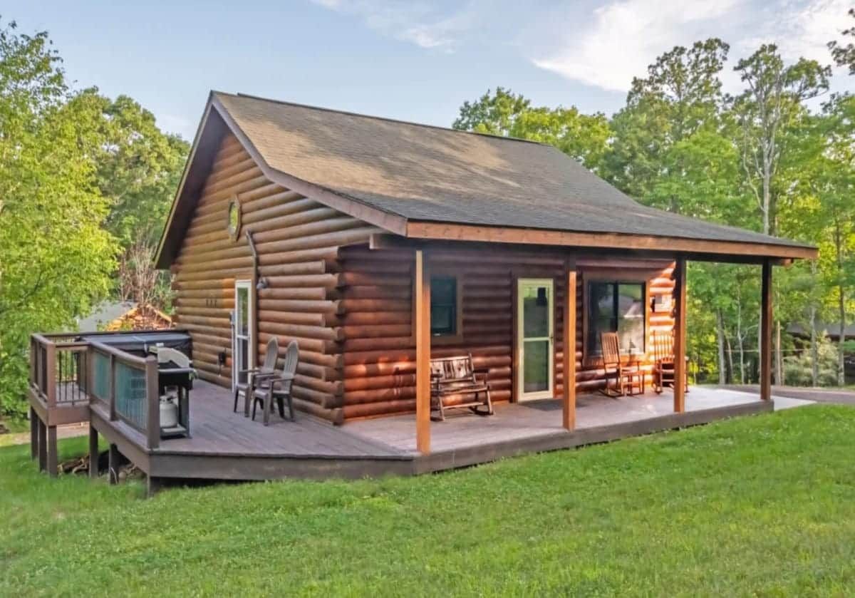 Una baita di legno con veranda, area salotto esterna e zona barbecue.