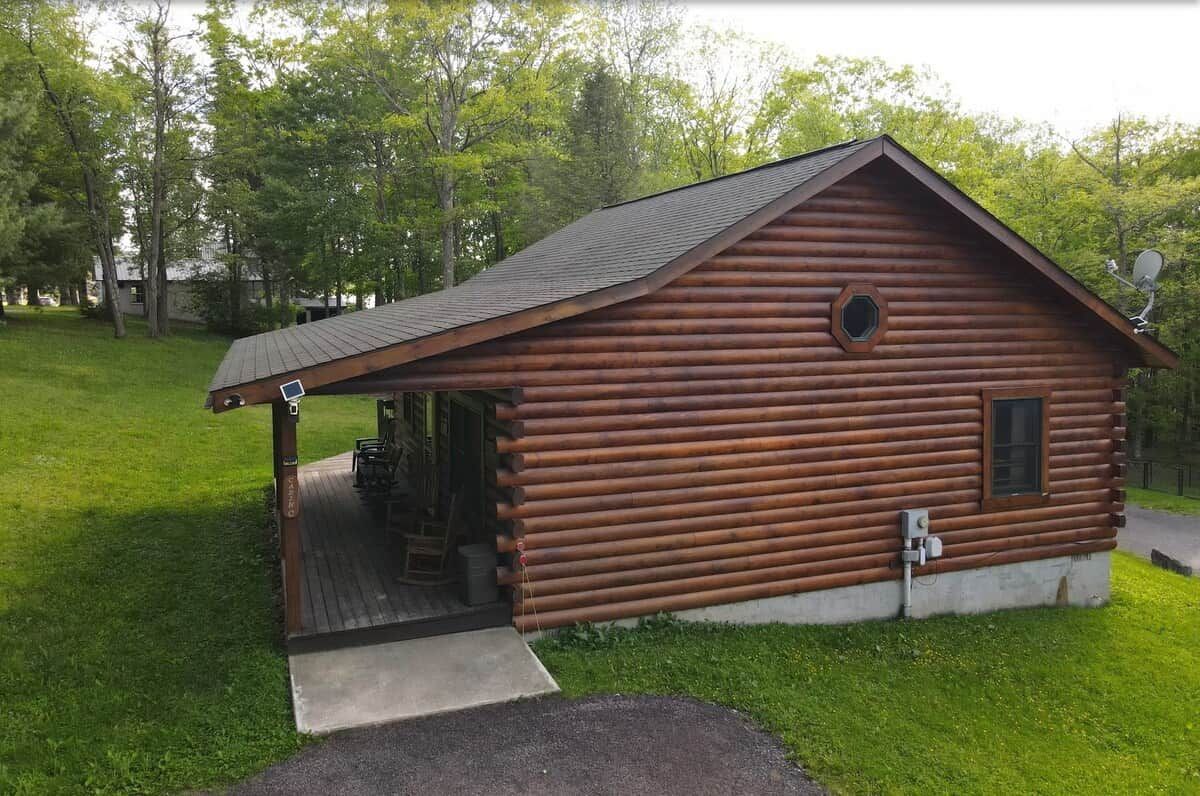 A wooden cabin with a porch, a small window, and a satellite dish.