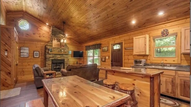 Ein Holzblockhaus-Interieur mit Esstisch aus Holz, Kamin, Küchenzeile und gemütlicher Sitzecke.