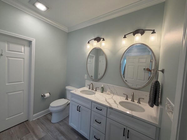 A bathroom with two sinks, a toilet, and a mirror with lights. - Beautiful True Blue 3 Bedroom 2 Bathroom Garden Home (Pawleys Island)